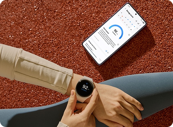 شخص يرتدي جالاكسي ووتش8 باللون الفضي. يظهر Energy Score الرقم 92 على الشاشة. بعد ذلك، يظهر جالاكسي إس26 إلترا مع أحدث مستوى Energy score.